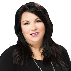 Smiling woman with dark, shoulder-length hair, wearing a black jacket over a black shirt